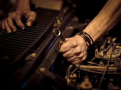 Hands tightening a bolt in an engine with a spanner
