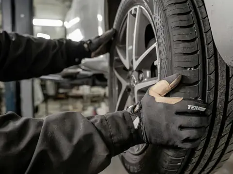 A mechanic in gloves fitting a tyre