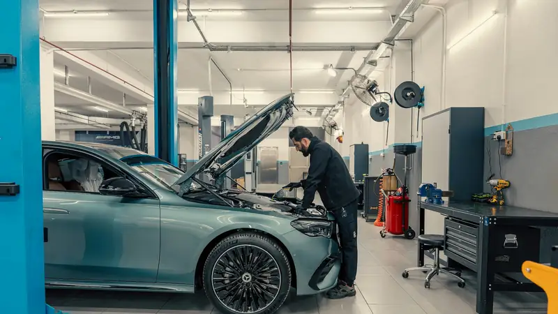 A bright workshop with a car on a lift and a mechanic at work